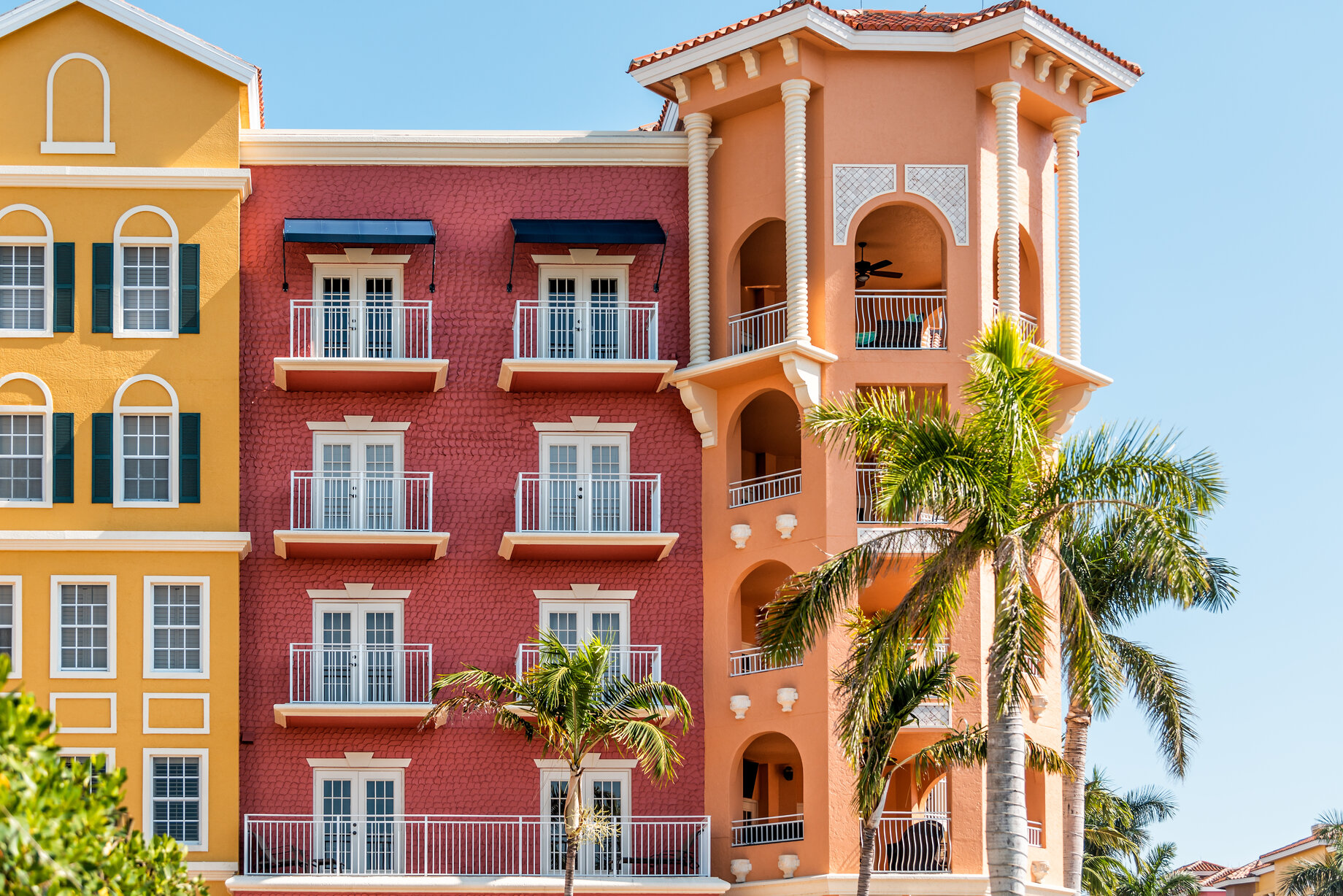 Florida condo, condominium colorful, red and orange multicolored buildings facade exterior with windows, palm trees, real estate property in Spain